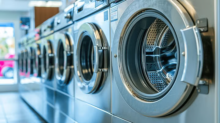 Row of industrial washing machines in a bright laundry facility